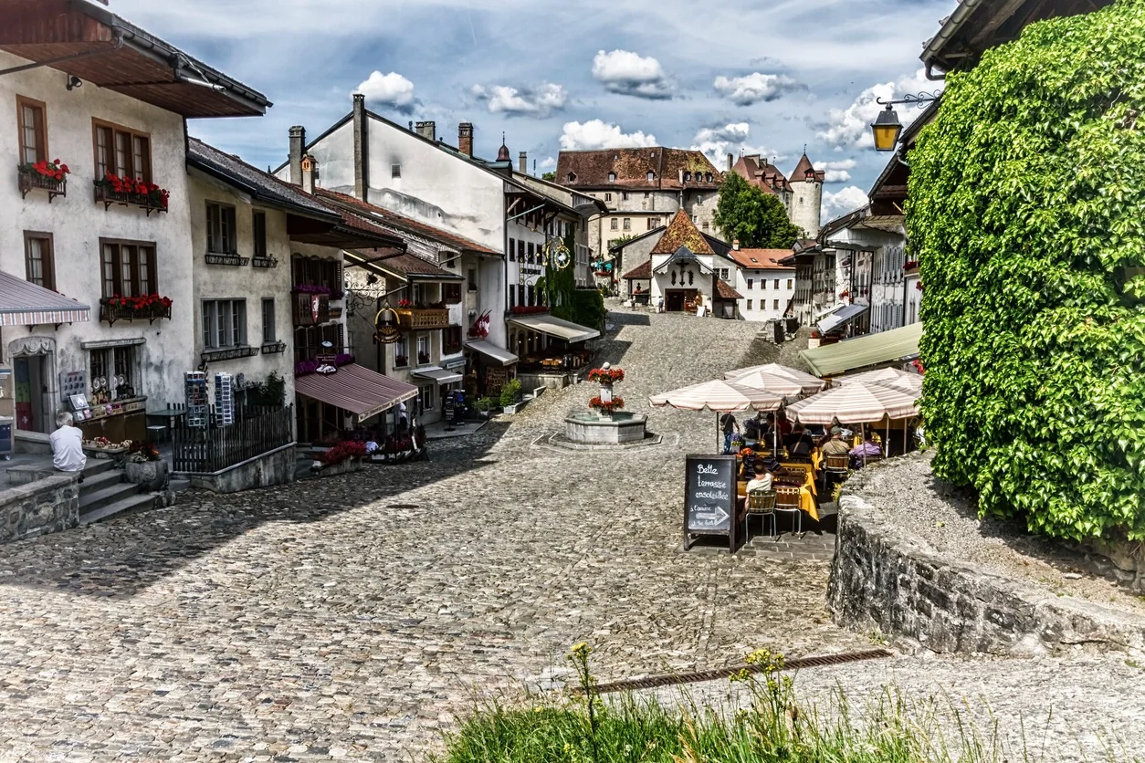 Calle empedrada del centro medieval de Gruyères con terrazas y fachadas tradicionales