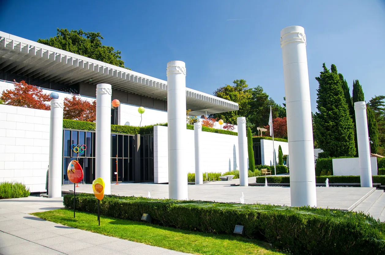 Entrada del Museo Olímpico de Lausanne con columnas blancas y vegetación